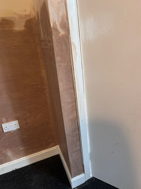 A render coat applied to a hallway wall ready for skimming