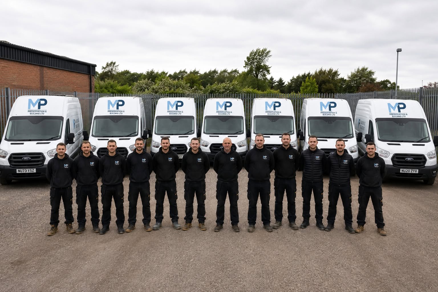 The MP Preservation & Building team standing in front of their fleet of liveried vans