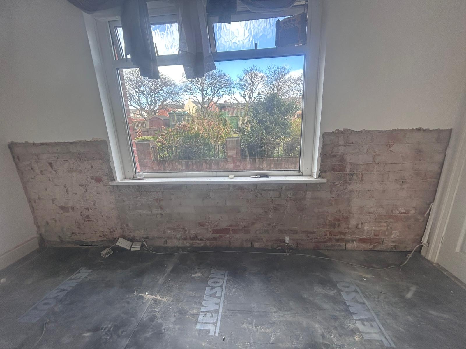 A lower wall hacked back to brick under a window ready for a new damp proof course