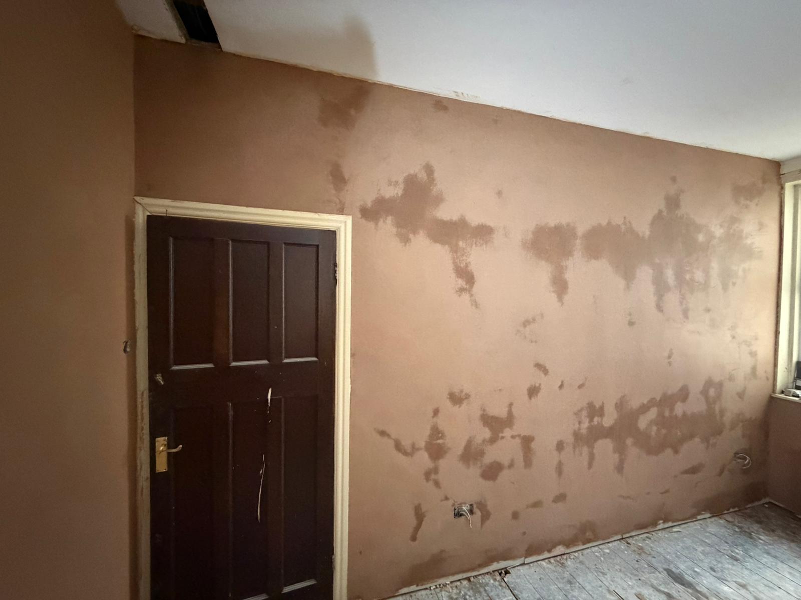 A hallway wall replastered with a scratch coat around the front door