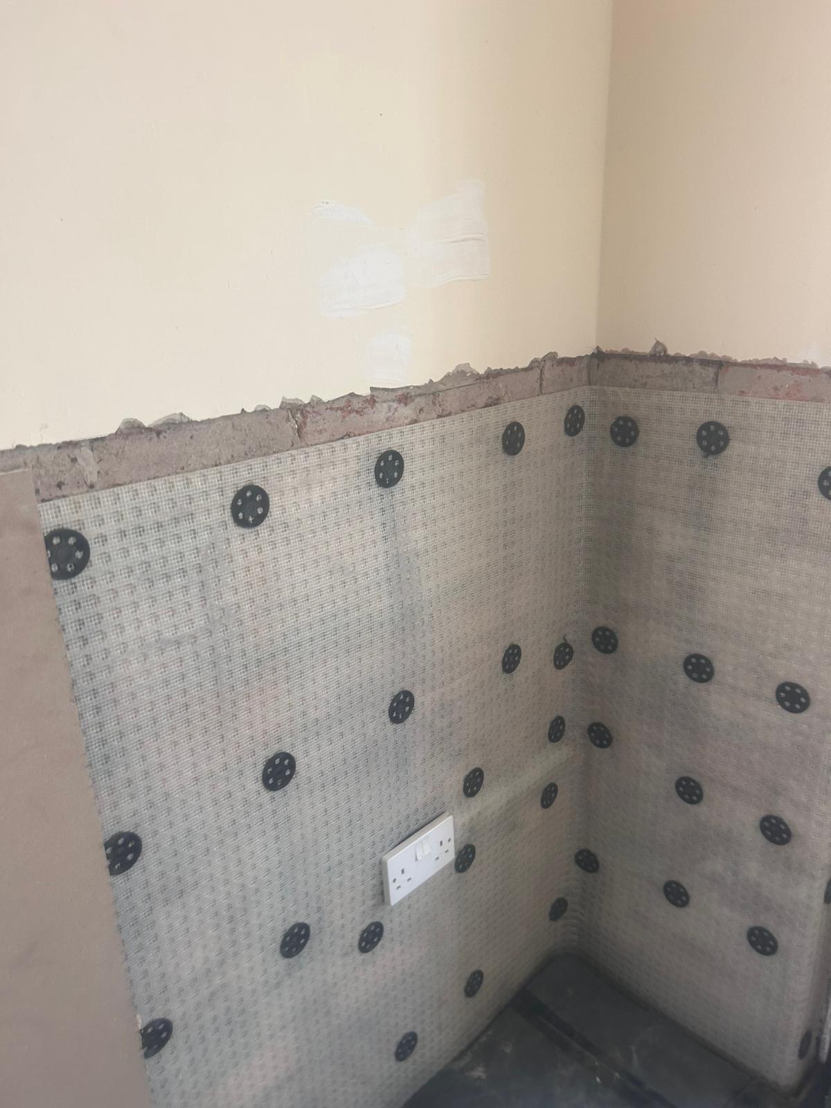Tanking membrane fixed to corner walls with sealed plugs before replastering